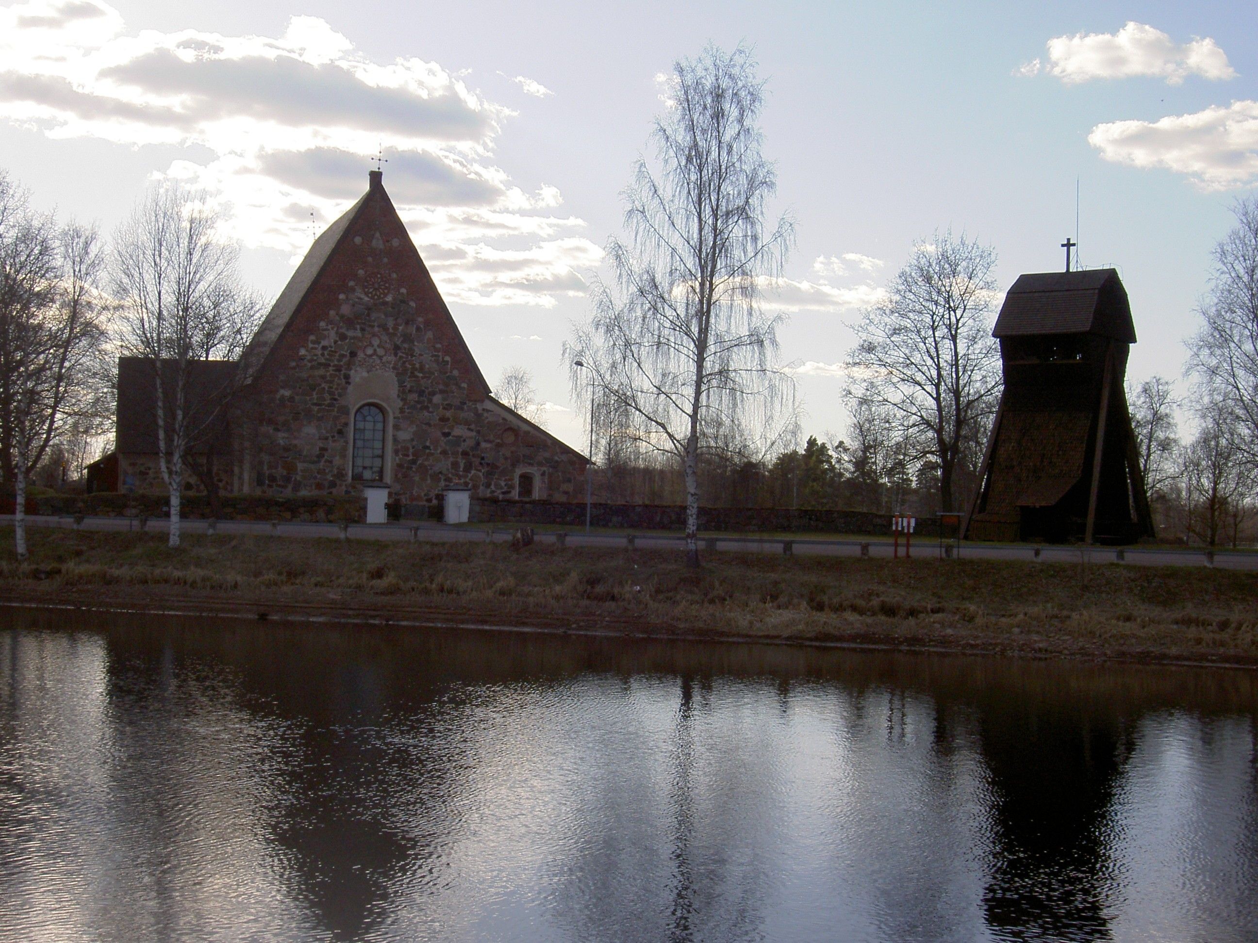 Torsångs kyrka och klockstapel i motljus vid vattnet i Borlänge kommun