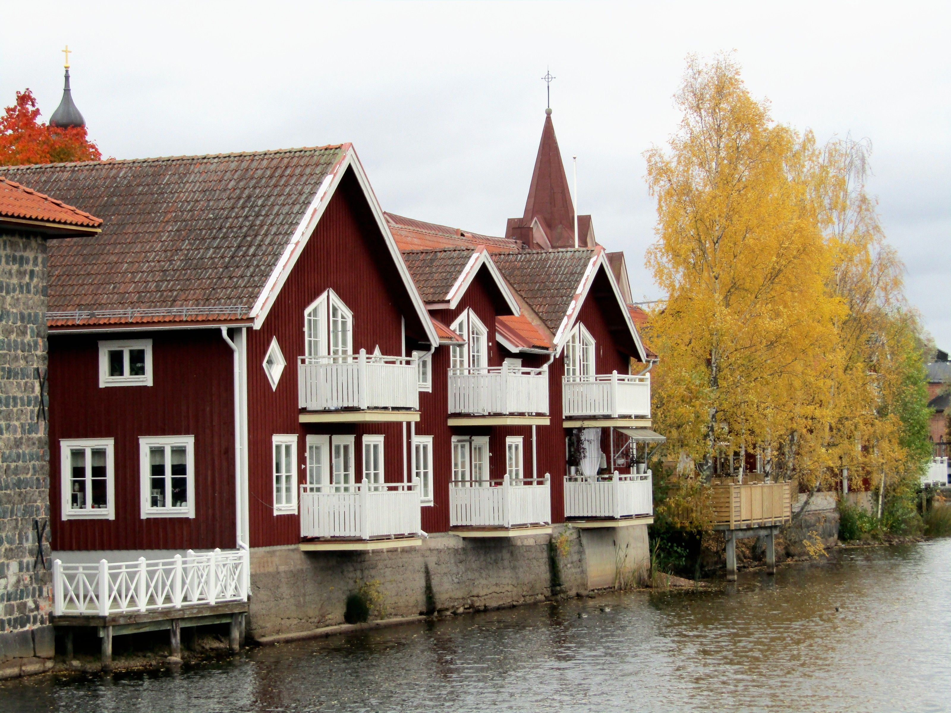 Röda trähus med vita balkonger längs Faluån i Falun