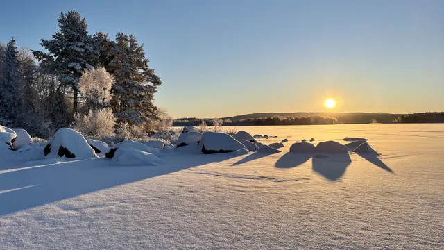 Soluppgång över en snötäckt Svärdsjön en kall vintermorgon