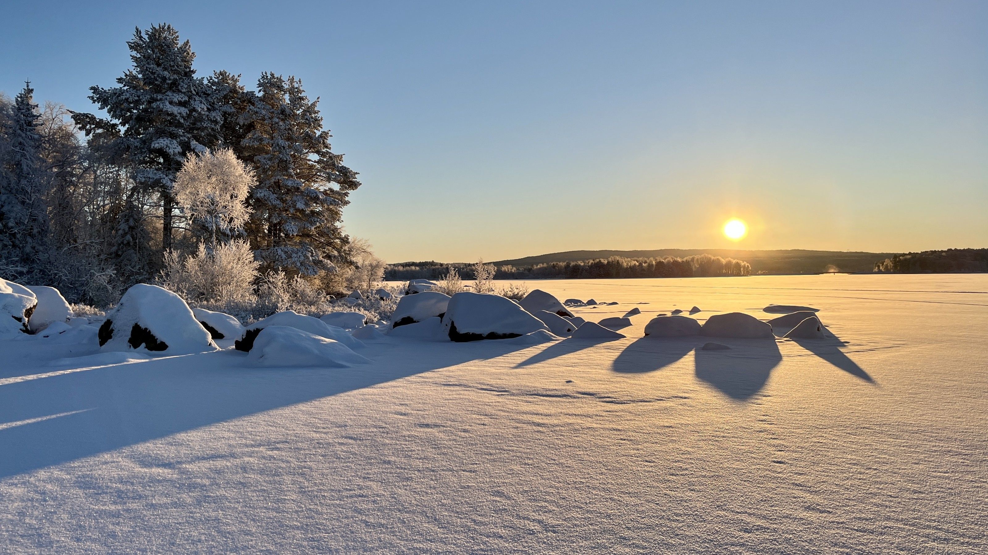 Soluppgång över en snötäckt Svärdsjön en kall vintermorgon