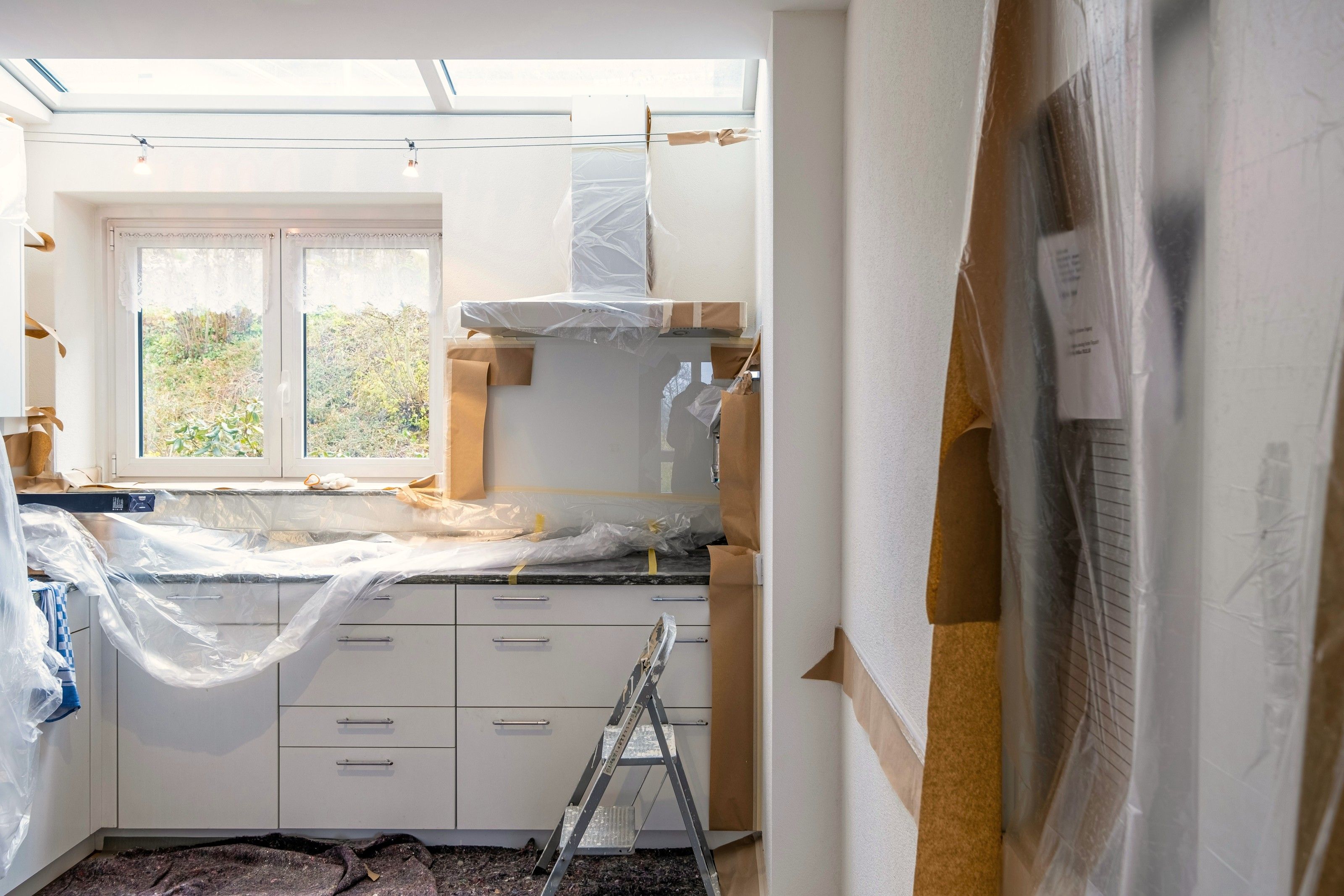 Kök under renovering med skåp och bänkar täckta av plast